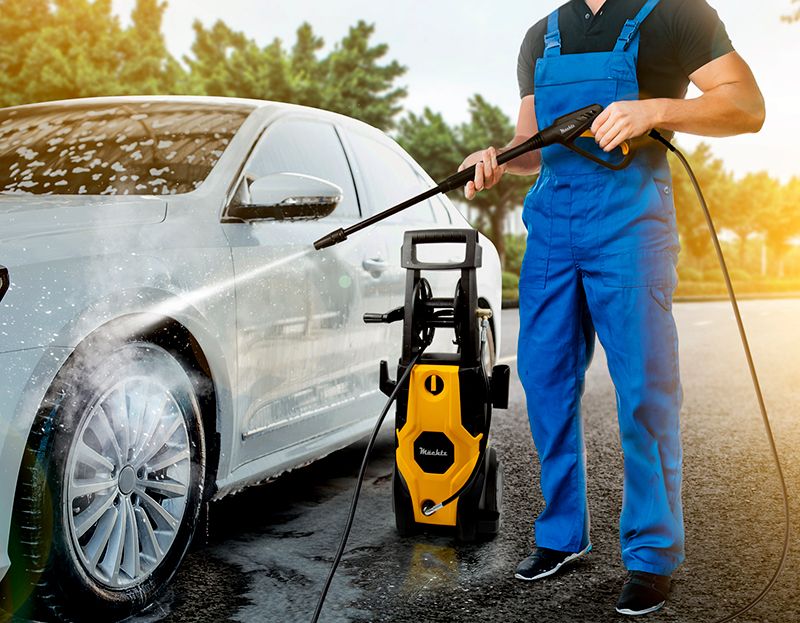 Мужчина моет мойкой высокого давления авто