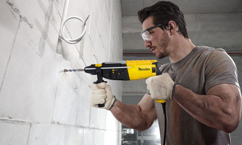 Человек работает перфоратором по стене