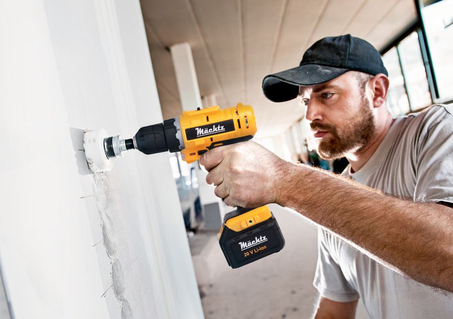 Мужчина работает шуруповертом в стене