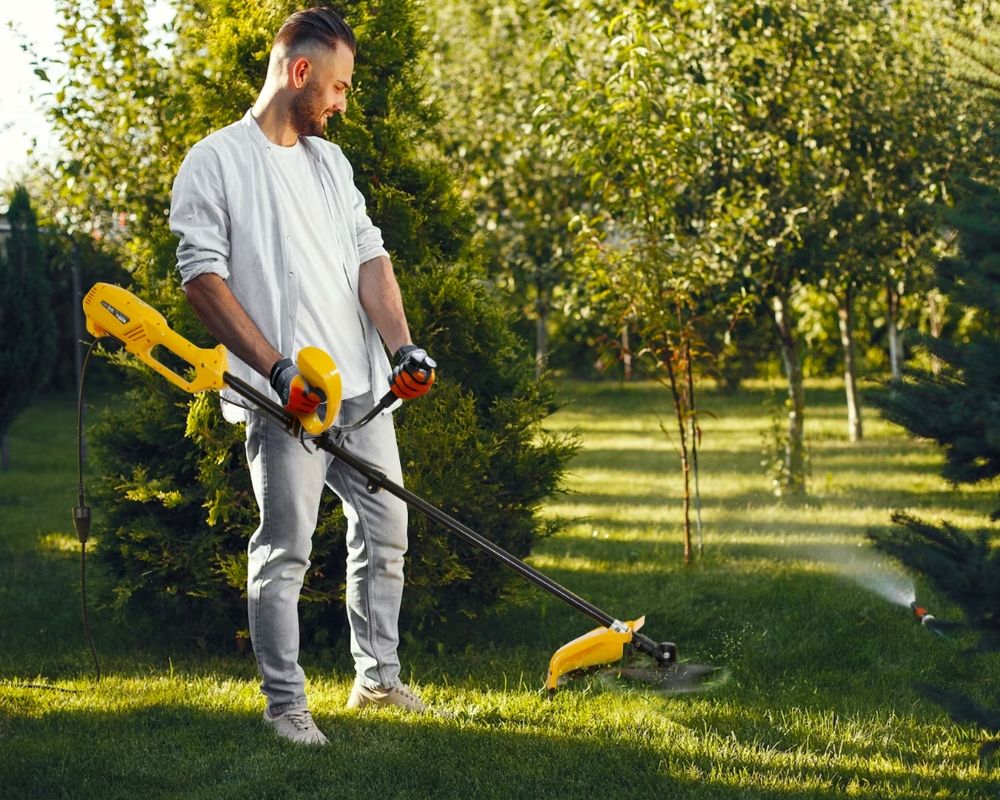 Чоловік стриже траву тримерами Mächtz