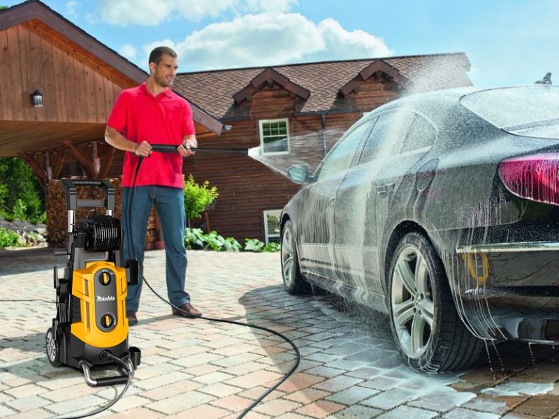Чоловік миє машину мийкою високого тиску