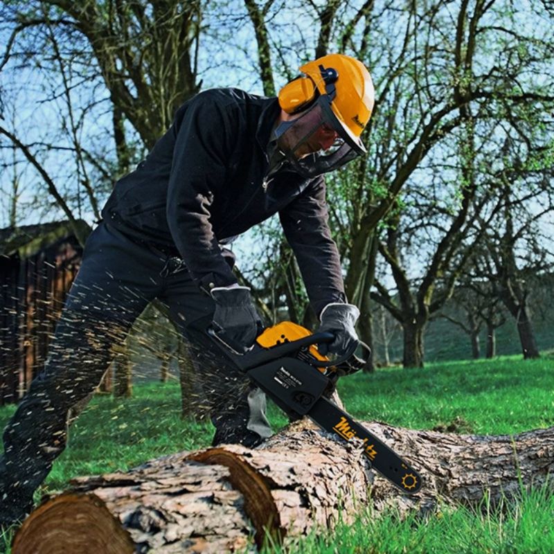 Мужчина пилит бревно бензопилой Mächtz