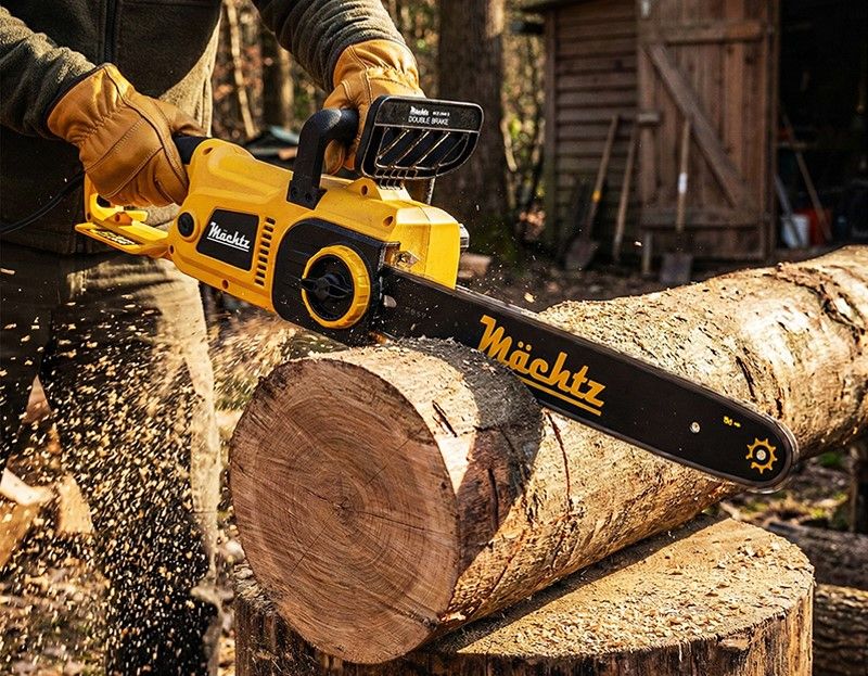 Мужчина пилит бревно бензопилой Mächtz