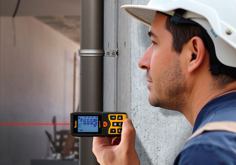 Фахівець вимірює відстань лазерною рулеткою на будівництві