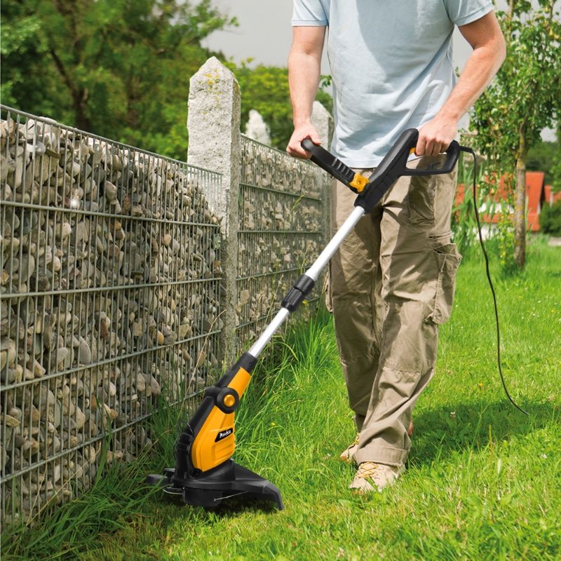 Обрізка трави тримером уздовж паркану