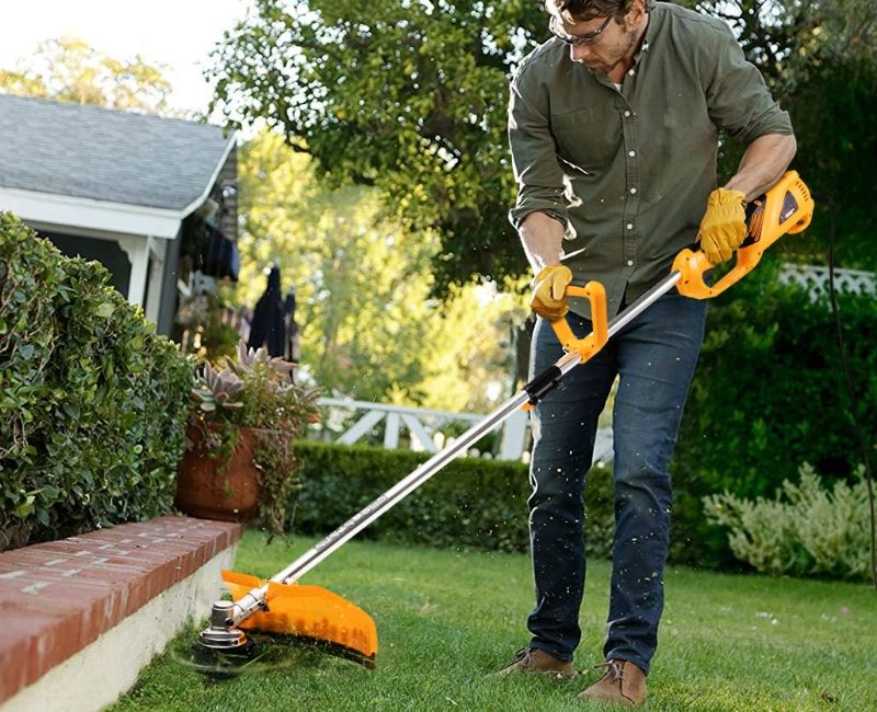 Робота тримера по краю газону біля будинку