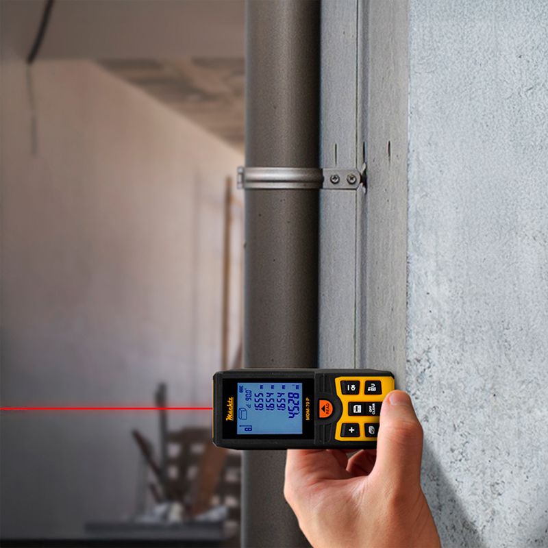 Специалист измеряет расстояние лазерной рулеткой на стройке