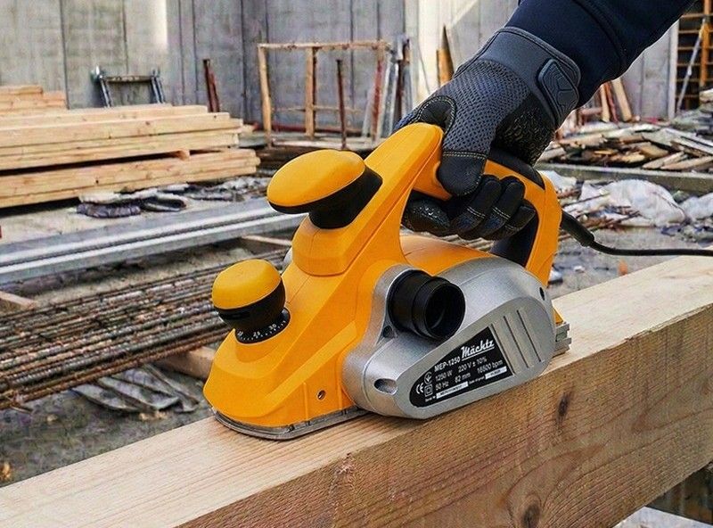 Мастер работает электрическим рубанком