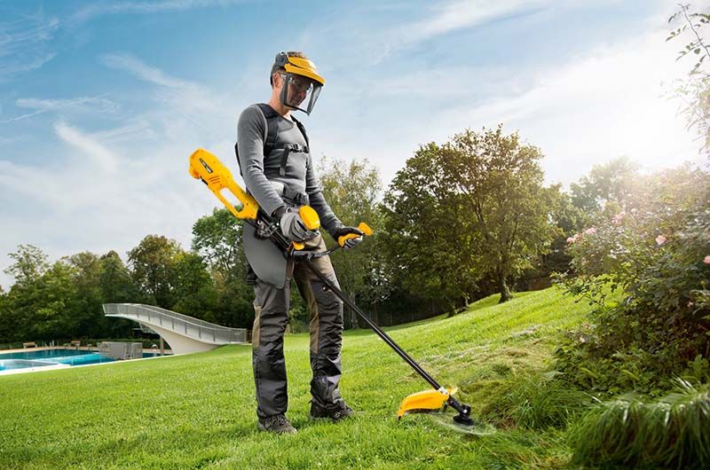 Чоловік працює електричним триммером на газоні