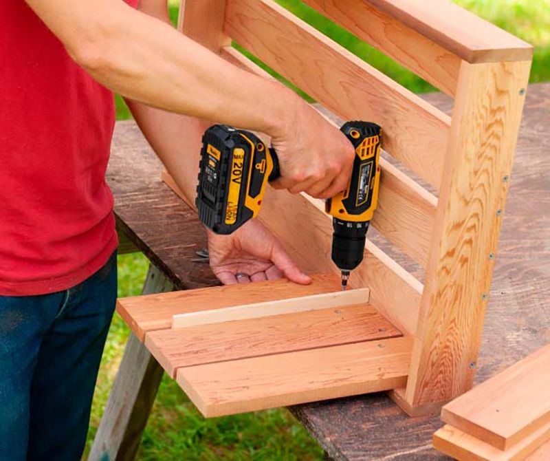 Человек работает шуруповёртом с деревом